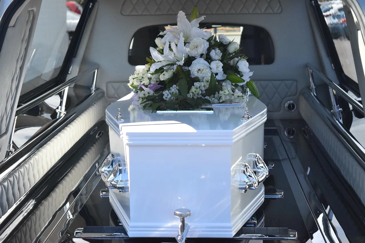 Cercueil blanc fleuri préparé dans le corbillard